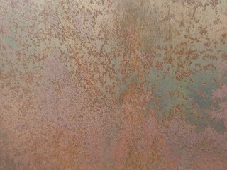 Close-up of a heavily rusted and oxidized metal surface, displaying a unique blend of earthy tones,...