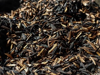A macro view of mixed charred and raw rice husks forming a rich, earthy texture background, perfect...
