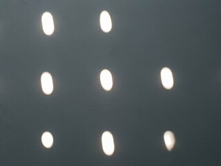 Abstract pattern of bright white light reflections on a textured dark grey surface, creating a...