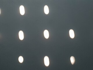 Blurred white light reflections on a dark grey textured surface creating an abstract and minimalist pattern.