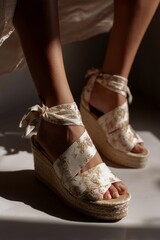 Close-up of floral espadrille wedges on a sunlit floor, showcasing elegant summer footwear fashion with natural textures.