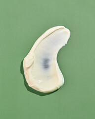 Texture of smeared ranch, mayonnaise, cheese or garlic sauce on a green background