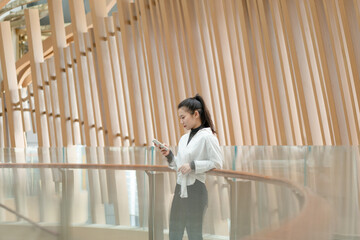 Beautiful woman leaning on railing using mobile phone