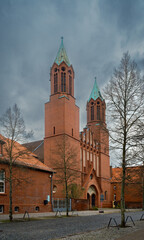 Dramatischer Wolkenhimmel über der denkmalgeschützten katholischen Kirche "St. Joseph" in Luckenwalde - Ansicht von Westen, Inschriften retuschiert