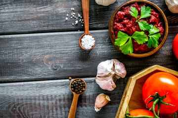 Homemade tomato sause near ingredients - garlic, spices - on dark wooden background top-down copy space