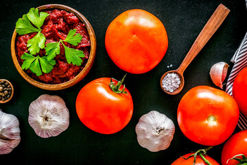 Homemade tomato sause near ingredients - garlic, spices - on black background top-down