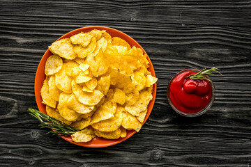 Potato chips served wiith ketchup on wooden background top view
