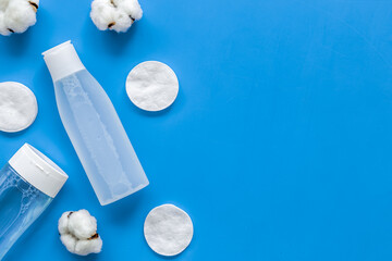 facial tonic, lotion and cotton pads for face care on blue background top view mock up