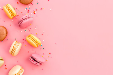 Brignt macarons for sweet break on pink background top view mock up