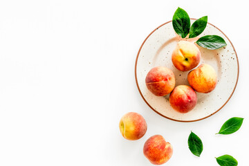 Summer fruits. Ripe red peaches on plate on white table top-down copy space