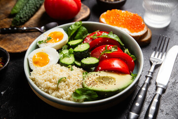 Couscous with boiled egg and vegetables in a plate on the table