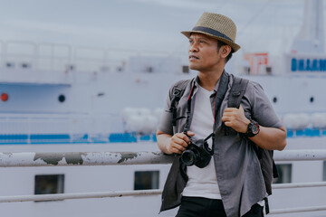 Travel photographer. Asian man tourist backpacker holding a digital camera while traveling summer...