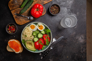 Couscous with boiled egg and vegetables in a plate on the table