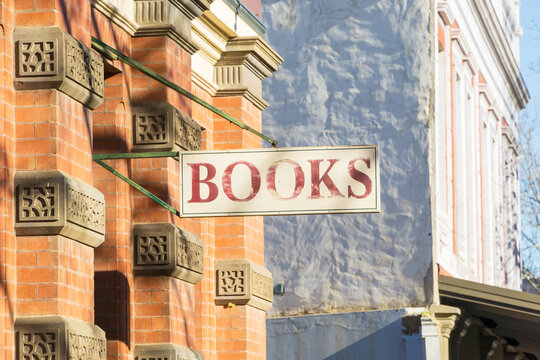 An old fashion "books" sign hangs from a historic brick building