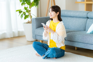 部屋でスマホを操作する若い女性