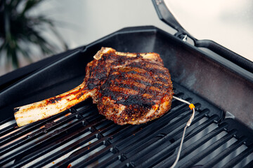 Delicious tomahawk steak grilling on bbq grill with thermometer probe