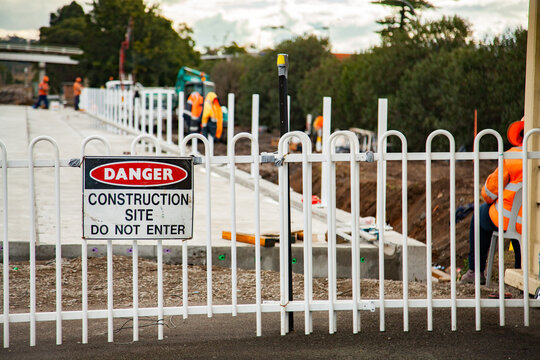 Danger construction site do not enter sign on a fence with construction site behind