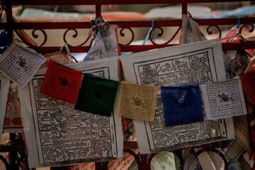 Colorful prayer flags hang on a decorative metal fence. The flags feature various symbols and texts, representing spiritual beliefs and traditions in Kalmykia.