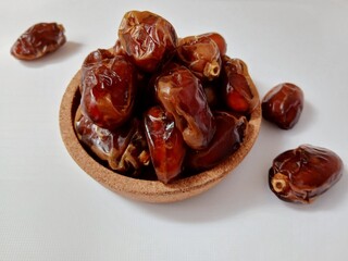 Dates in a glass bowl falling on a white background.