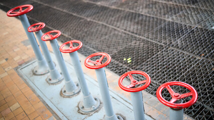 Row of old retro valve wheels painted red selective focus with extension device over out of focus...
