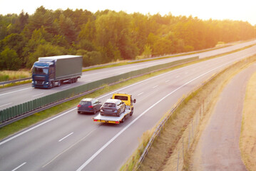 Car Being Towed on Flatbed Truck Along Highway at Sunset