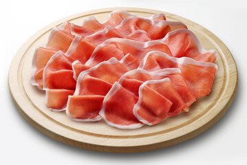 Round wooden chopping board with sliced Parma ham