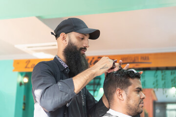 Hairdresser cutting hair of customer in barbershop