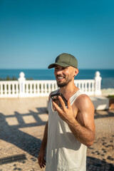 Smiling travel blogger using smartphone at beach resort