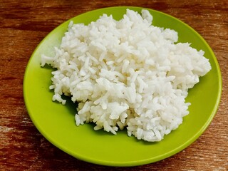 Steamed rice on plate isolated on wooden background. Carbohydrate menu