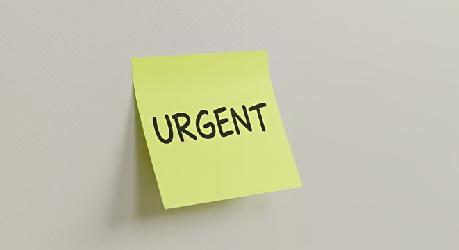 Urgent reminder on a bright yellow sticky note, stuck to a light grey wall, conveying a sense of importance and time sensitivity.
