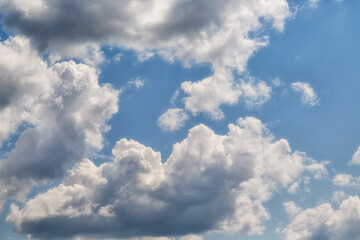 Different white cumulus clouds with edges illuminated by sunlight in a blue sky close-up, sky...