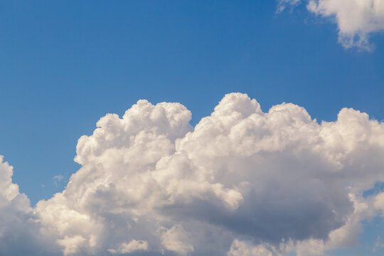 Top edge of a white fluffy cloud in a blue sky close-up, a heavenly landscape with a large cloud in the sky, clouds in bright daylight during summer.