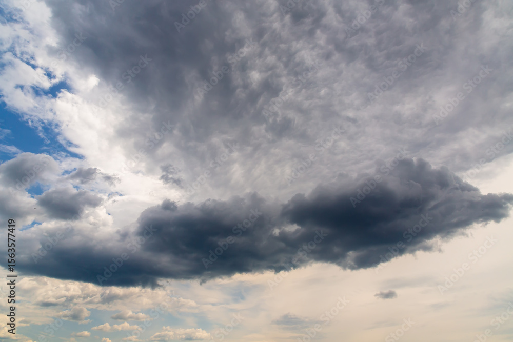 Poster a large dark gray cloud among other cumulus clouds as a change in weather, cloudy weather changing a