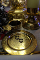 Wedding rings on a golden tray and a cup of wine on a throne in a church. Church wedding.