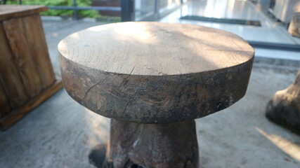 Fototapeta premium Simple round wooden stool or side table outdoors, showcasing natural wood grain and texture. Rustic furniture piece with sunlight on top, perfect for natural, home, or minimalist designs. Blurred back