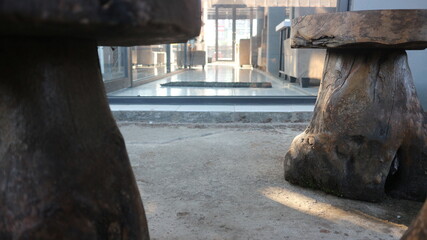 Close-up of rustic wooden stool legs or tree trunk base, showcasing natural bark texture, cracks,...