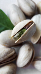 Pistachios and Fresh Green Leaf Scattered on a White Background, Close-up