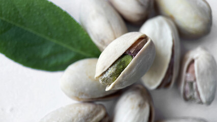 Pistachios and Fresh Green Leaf Scattered on a White Background, Close-up