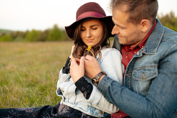 Man putting flower in woman's hair in a meadow