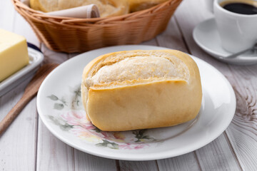 French bread or salt bread with butter and coffee over white wooden table
