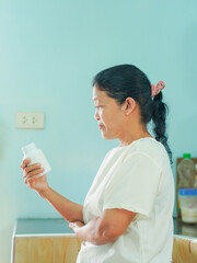 Senior Asian woman holding drugs for concept health care and medical. Healthy lifestyle people medicine bottle with pill for home care wellness health. Elderly care patient. Female reading drug labels