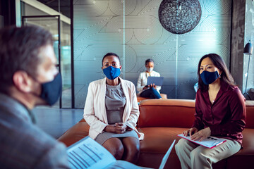 Diverse business team wearing face masks having office meeting during pandemic