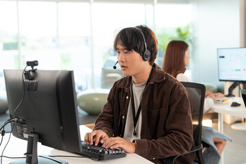 Focused tech support professional wearing headset is working computer modern office environment,...