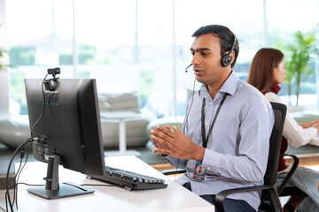 Professional tech support representative wearing headset provides customer assistance while working...