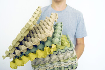 Man holding a stack of used egg cartons made of recycled paper. Concept of waste sorting,...