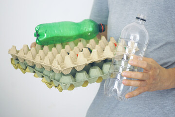 Close-up of person holding plastic bottles and paper egg cartons for recycling. Concept of zero...