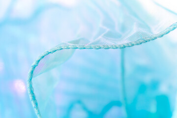 Close-Up of Light Blue Translucent Fabric with Wavy Edge – Delicate Sheer Texture and Stitching...