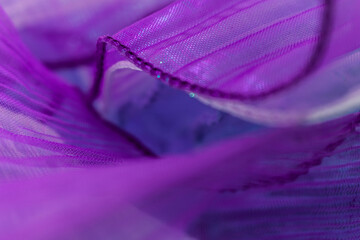Close-up of semi-transparent purple fabric with striped texture, folds, and stitching – abstract...