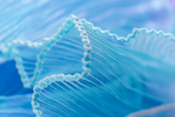 Close-Up of Light Blue Translucent Fabric with Pleated and Ruffled Edges – Delicate Wavy Texture...