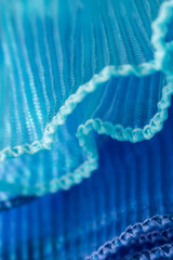 Close-up of pleated translucent fabric in soft blue hues with delicate waves and folds, ideal for...